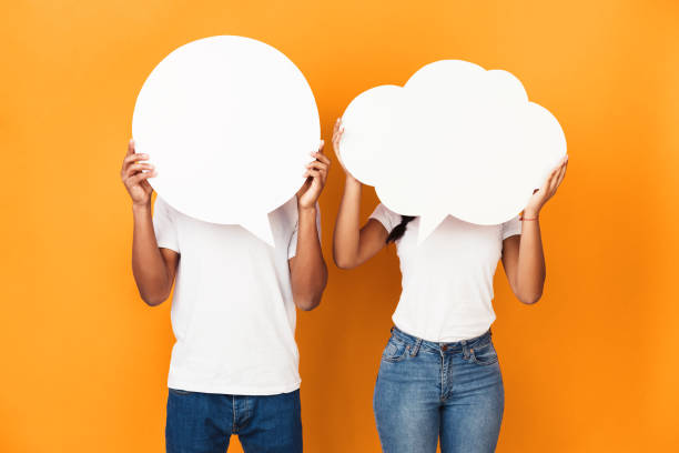 Couple holding speech bubbles over orange background Couple holding speech bubbles, closing faces over orange background quotes about family love stock pictures, royalty-free photos & images