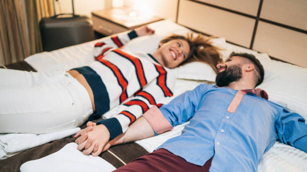 Couple in love lying down on bed in hotel room stock photo