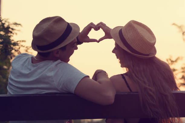 Couple in love making heart shape outdoors. stock photo