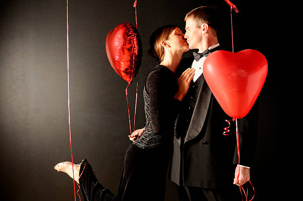 Couple kissing with heart shaped balloons stock photo