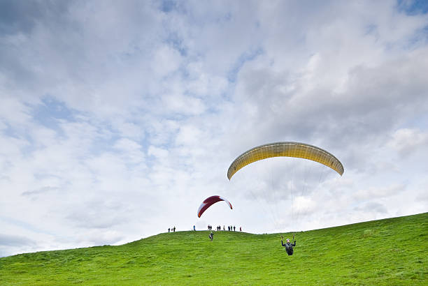 Paragliding at Gasworks Park Seattle, Washington, USA - February 18, 2013: A couple lands paragliders on a grassy slope while a crowd of people watches. This photograph was taken at Gasworks Park. jeff goulden inspiration stock pictures, royalty-free photos & images