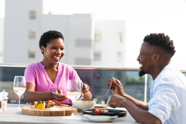 Couple laughing together enjoying lunch at a rooftop cafe stock photo