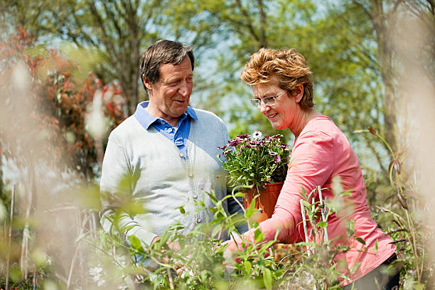 couple looking at plants at garden center - pensioen nederland stockfoto's en -beelden