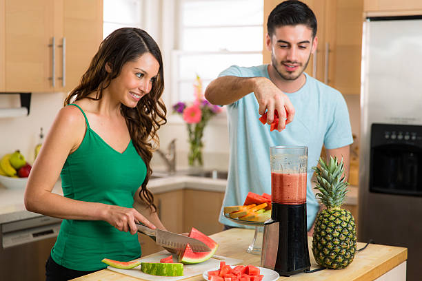 Couple lovers man woman make a smoothie fresh fruits blender stock photo