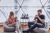 istock Couple - man and woman are sitting on bag chairs and drinking coffee in the geodome 1390016102