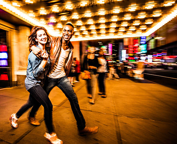Couple New York city lifestyle Couple having fun at night on Broadway, New York City. nightlife stock pictures, royalty-free photos & images