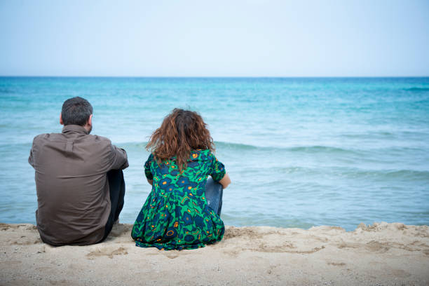 Couple of adults in crisis by the sea Couple of adults in crisis by the sea divorce beach stock pictures, royalty-free photos & images