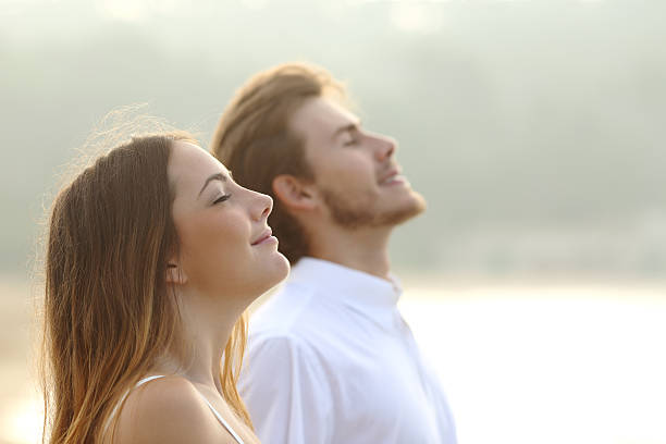 Couple of man and woman breathing deep fresh air Profile of a couple of man and woman breathing deep fresh air together at sunset inhaling stock pictures, royalty-free photos & images