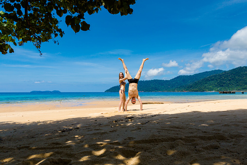 Landscape with young tourist couple on tropical Tioman island in Malaysia. Beautiful seascape of south east asia on Tekek beach.