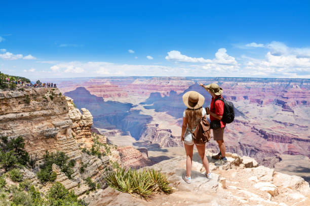 Couple on top of the mountain, looking at beautiful summer mountain  landscape. Couple on top of the mountain, looking at beautiful summer mountain  landscape. Friends on hiking trip enjoying view of Colorado river. South Rim. Grand Canyon National Park, Arizona, USA. grand canyon national park stock pictures, royalty-free photos & images