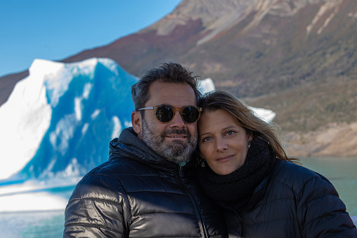 Loving couple in their 47 years old embracing and looking at camera- Glaciar Perito Moreno - Patagonia