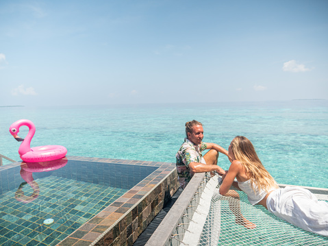 Young couple enjoying their honeymoon in luxury bungalow over sea