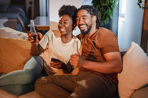 Couple relaxing on the couch at home, watching sports and cheer for their team stock photo