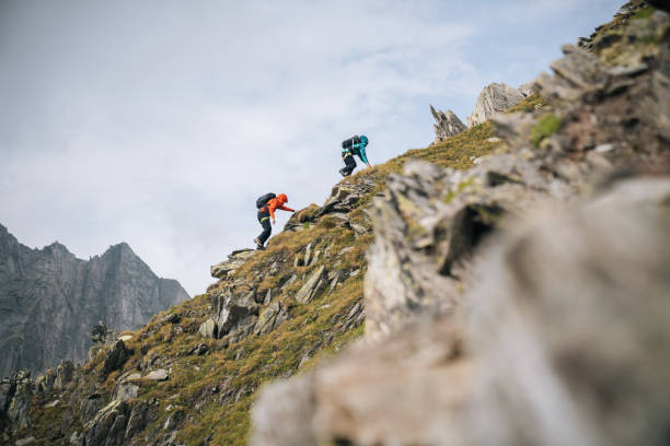 couple scramble up mountain ridge - motivatie stockfoto's en -beelden