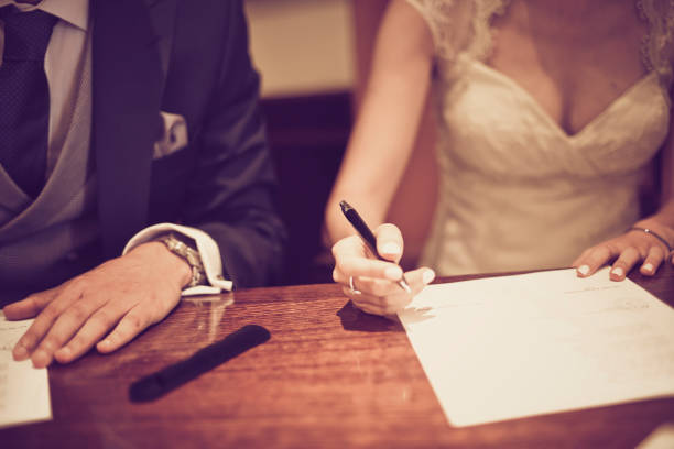カップルは、選択的な焦点とヴィンテージトーンで詳細に撮影し、彼らの結婚式の日に署名します。 ストックフォト