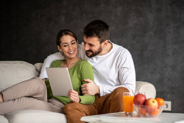 Couple sitting and watching videos on tablet. stock photo