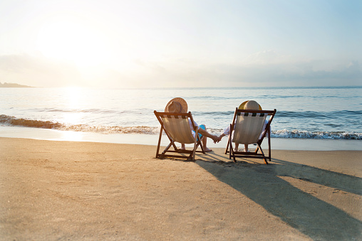 Couple sitting on deck chair at beach.