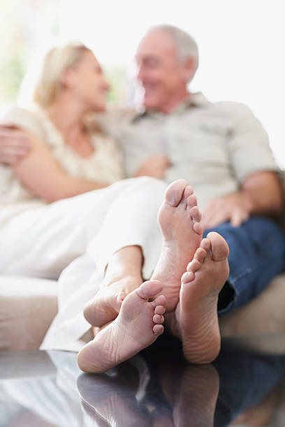 Couple sitting on sofa with feet propped on table, focus on feet