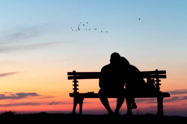 Couple sitting on the bench above horizon stock photo