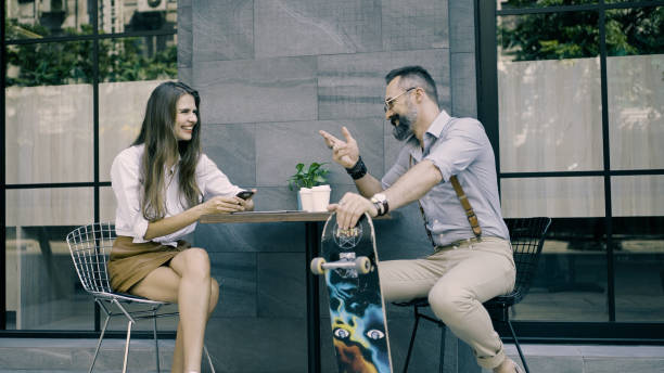 Couple sitting together at outdoor café with their skateboard stock photo