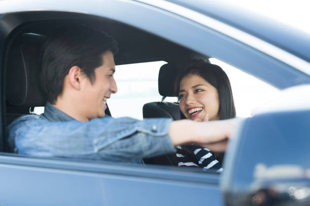 A couple talking while driving. A young couple who makes fun conversations while driving. shy japanese woman stock pictures, royalty-free photos & images