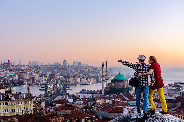 Couple travelling together staying on roof and overlooking cityscape stock photo