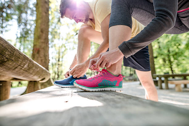 Couple tying shoes Couple tying their exercise shoes. getting dressed stock pictures, royalty-free photos & images