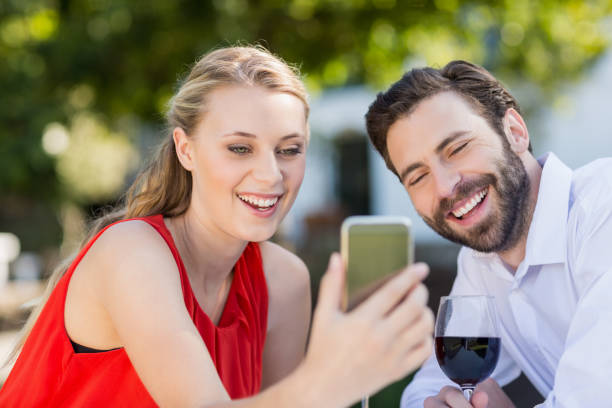 Couple using mobile phone in a restaurant Happy couple using mobile phone in a restaurant cougar woman stock pictures, royalty-free photos & images