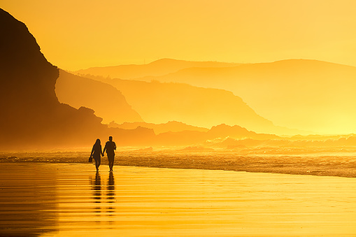 couple walking in the beach at the sunset