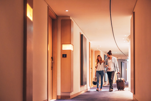 Couple walking with their luggage in the hotel corridor