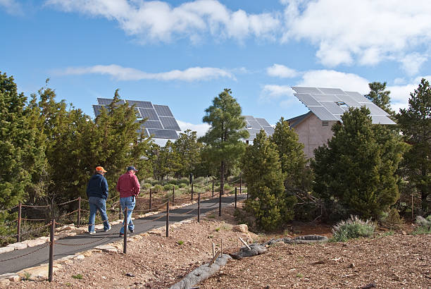 Couple Walks by Solar Panels at Grand Canyon Visitor Center Grand Canyon National Park, Arizona, USA - May 17, 2011: The National Park System is often on the leading edge of conservation and energy efficiency. This couple is walking by the solar panels at the Grand Canyon Visitor Center near Mather Point. jeff goulden grand canyon national park stock pictures, royalty-free photos & images