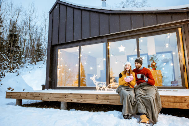 couple warming up near the house during the winter holidays - family modern house window imagens e fotografias de stock