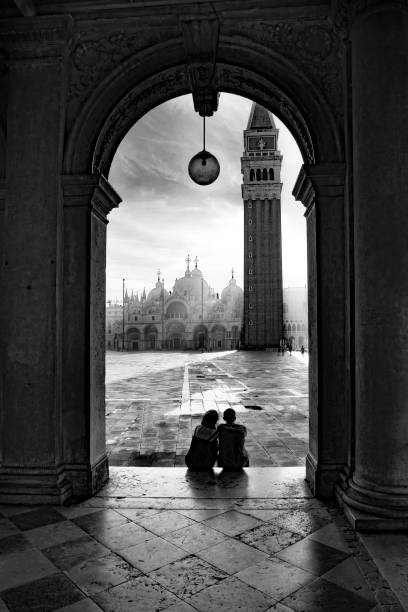 couple watches the sunrise  at St. Mark's square with view to the basilica di San Marco in morning light stock photo