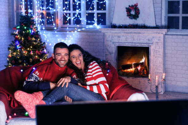 Couple watching TV at home Young couple resting at home and watching TV in front of fireplace. spectator stock pictures, royalty-free photos & images