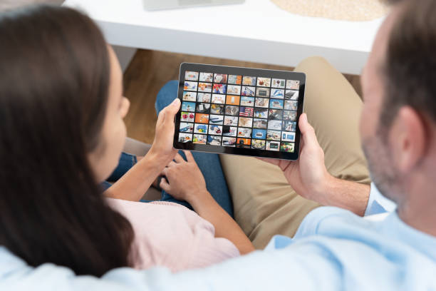 Couple watching TV series on tablet Couple watching TV series on tablet. Video on demand service. video on demand stock pictures, royalty-free photos & images