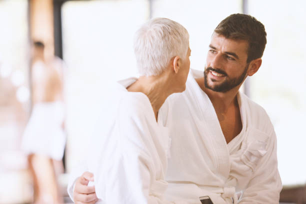 Couple with big age gap Young man and a mature woman are having a romantic weekend at the spa. They are sitting by the pool wearing cozy bathrobes. cougar woman stock pictures, royalty-free photos & images