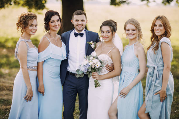 couple with bridesmaids elegant and stylish bride along with her four girlfriends in blue dresses and her husband standing in a park bridesmaid dresses stock pictures, royalty-free photos & images