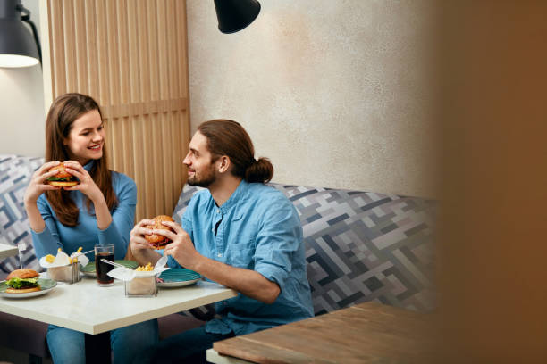 Echtpaar met hamburgers In Cafe​​​ foto