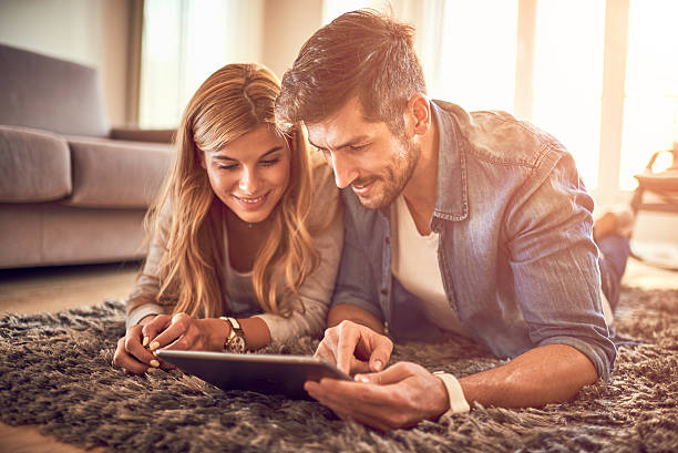 Couple with digital tablet Caucasian couple using digital tablet on the floor mid adult couple stock pictures, royalty-free photos & images