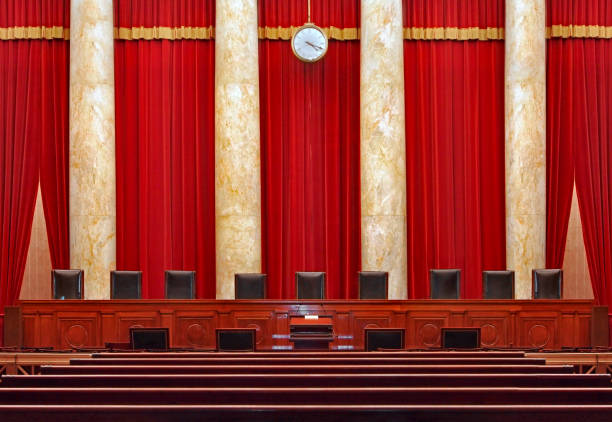 Court room interior at the United States Supreme Court Washington, DC, USA - June 9, 2014:  The seats for the nine powerful judges of the Supreme Court face the courtroom against a red backdrop. supreme court building stock pictures, royalty-free photos & images