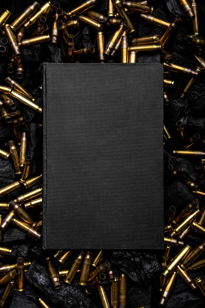 Cover of a black closed book. Empty gun cases lying on charred coals. Dark background. stock photo