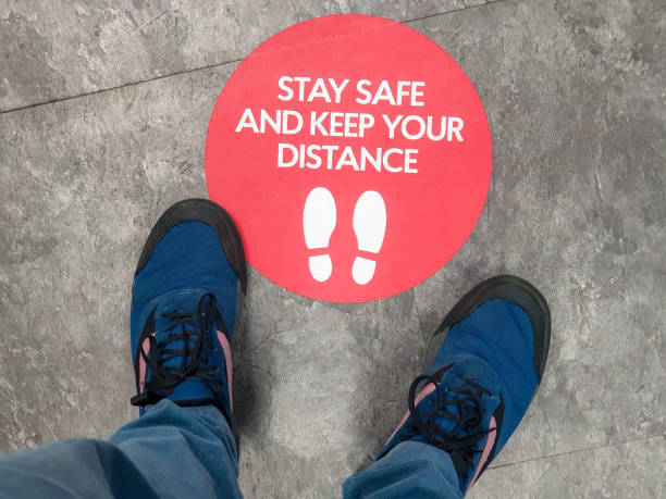 A sign on the floor of a shop, advising customers regarding social distancing guidelines.
