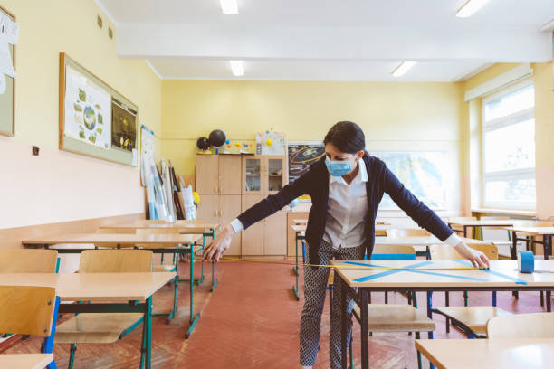 Covid-19 The teacher marks empty places in the classroom The teacher measuring and marking places in the classroom that are to be empty after students return to school after the coronovirus pandemic. Covid-19 school building stock pictures, royalty-free photos & images