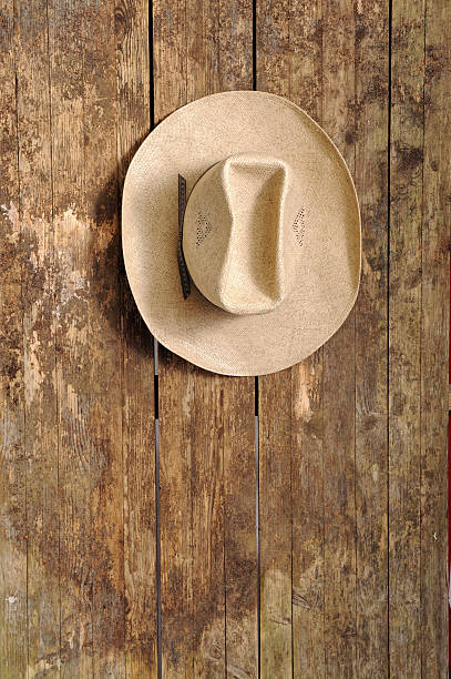 cowboy hat hangin on an old wooden wall stock photo