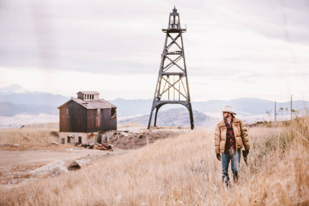 Cowboy walking through field with oil drill and barn stock photo