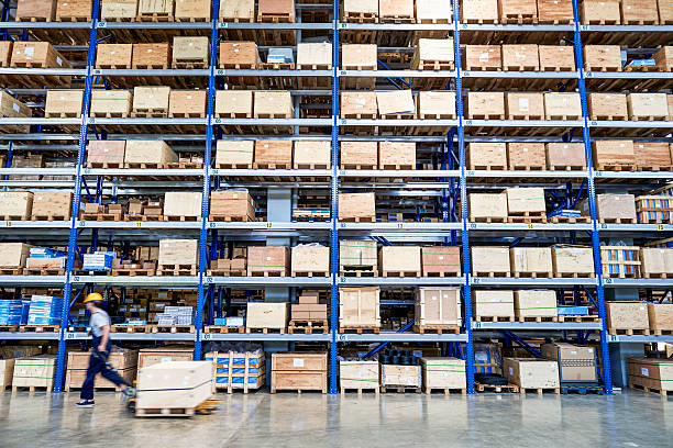 Coworker carrying cardboard box in warehouse. Cardboard boxes on shelves in warehouse. Storhouse. market retail space stock pictures, royalty-free photos & images