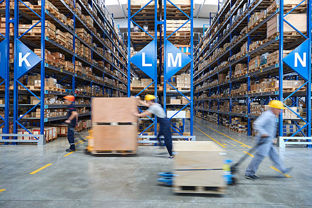 Coworkers carrying cardboard box in warehouse. stock photo