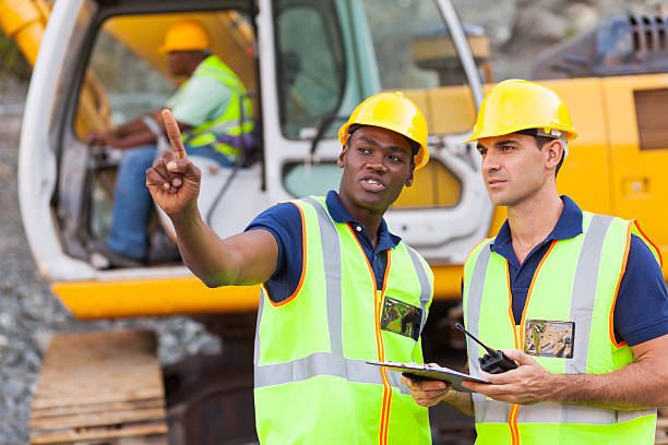 co-workers talking at construction site stock photo