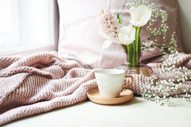 Cozy Easter, spring still life scene. Cup of coffee, pink knitted plaid and floral bouquet in vase on windowsill. Vintage feminine styled photo. Composition with tulips, hyacinth and Gypsophila flowers Cozy Easter, spring still life scene. Cup of coffee, pink knitted plaid and floral bouquet in vase on windowsill. Vintage feminine styled photo., composition with tulips, hyacinth and Gypsophila flowers sunday morning coffee stock pictures, royalty-free photos & images