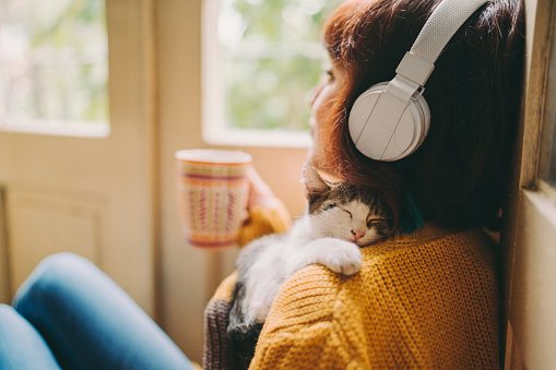 Woman at home listening to music and drinking coffee